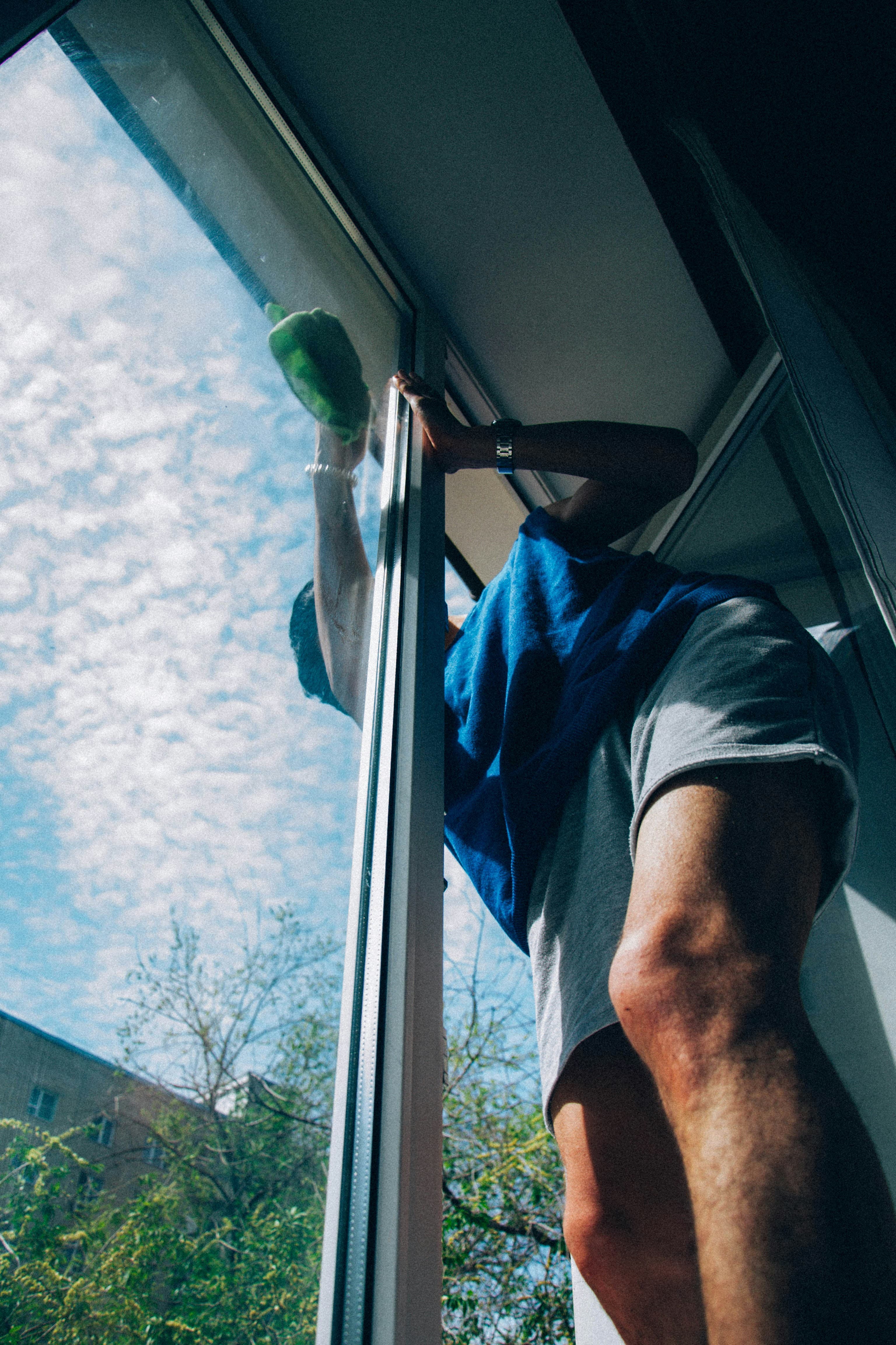 Schoonmaker zemt een raam tegen een strakblauwe lucht